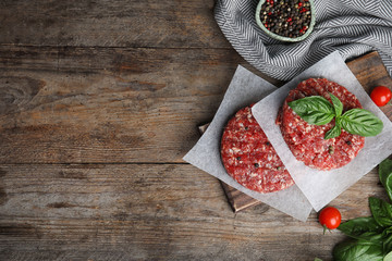 Flat lay composition with raw meat cutlets for burger on wooden table. Space for text