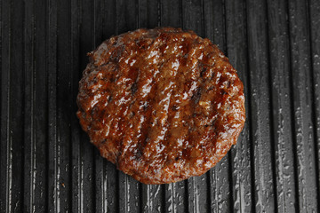 Prepared meat cutlet for burger on grill, closeup