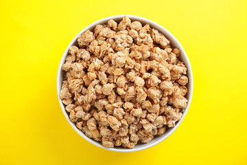 Bowl with healthy granola on yellow background, top view
