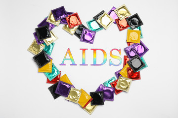 Frame made of colorful condoms with word AIDS inside on white background, top view. Safe sex