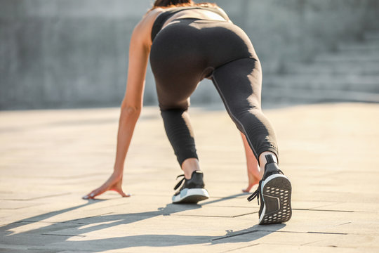 Sporty young woman in crouch start position outdoors