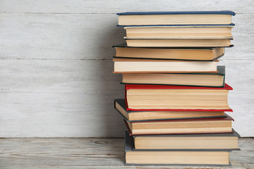 Stack of hardcover books on wooden table against white background. Space for text