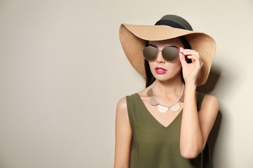 Fototapeta na wymiar Beautiful woman in stylish sunglasses and hat on beige background. Space for text