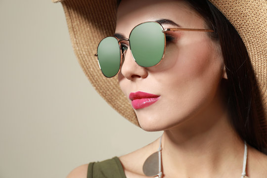 Beautiful woman in stylish sunglasses and hat on beige background