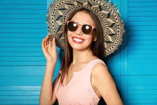 Beautiful woman wearing sunglasses and hat near blue wooden folding screen