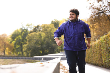 Young overweight man running in park. Fitness lifestyle