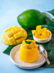 Mango Mousse on blue background with copy space left. Delicious yellow mango mousse with sliced...