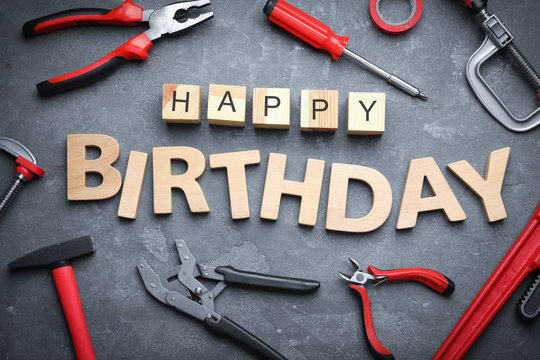 Tools and words HAPPY BIRTHDAY on grey stone background, flat lay