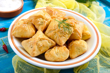 Tasty homemade mini chicken pies in a bowl on a wooden background. One of the types of samsa.