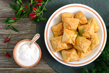 Tasty homemade mini chicken pies in a bowl on a wooden background. One of the types of samsa. Top view.