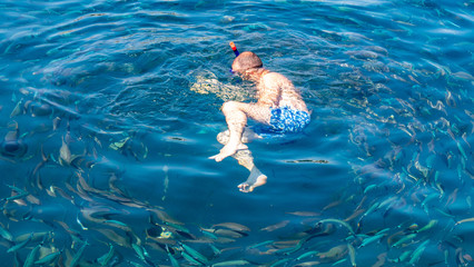 A man swims in the blue water of the sea