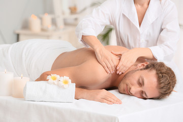 Obraz na płótnie Canvas Young man receiving massage in spa salon