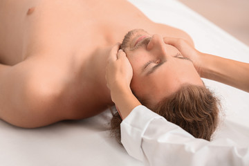 Fototapeta na wymiar Young man receiving facial massage in spa salon