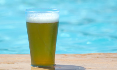 Glass with beer near the water on the beach