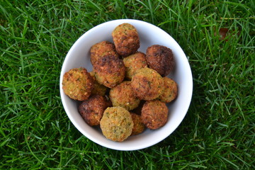 falafels in the white bowl on the green grass. fresh tasty homemade falafel balls. chickpeas balls with seasoning.