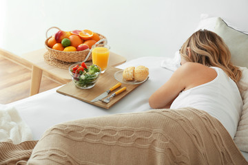 Obraz na płótnie Canvas Tray with tasty breakfast on bed of sleeping woman