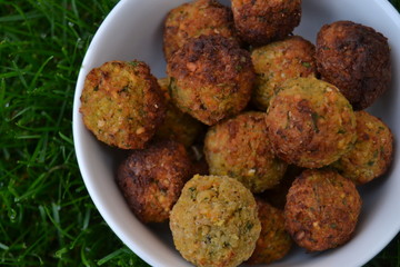 falafels in the white bowl on the green grass. fresh tasty homemade falafel balls. chickpeas balls with seasoning.