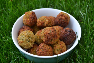falafels in the white bowl on the green grass. fresh tasty homemade falafel balls. chickpeas balls with seasoning.
