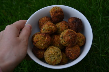falafels in the white bowl on the green grass. fresh tasty homemade falafel balls. chickpeas balls with seasoning.
