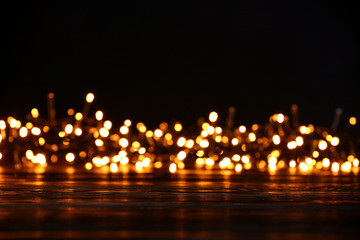 Wooden table and blurred Christmas lights, closeup