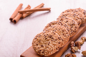 Cookies of sesame seeds, sunflower seeds and other spices on a wooden plate. Bright key