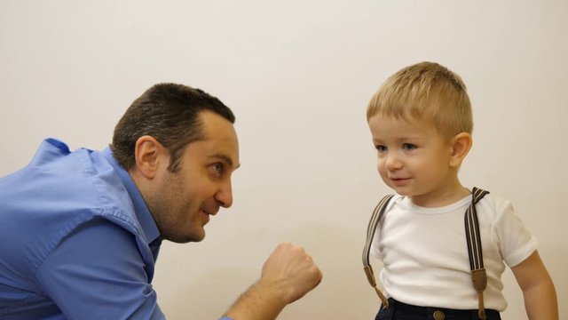 Portrait of father and blue eyes boy arm wrestling force play