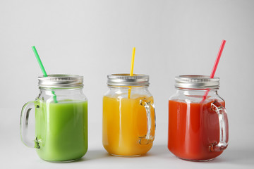 Mason jars of fresh juice on grey background