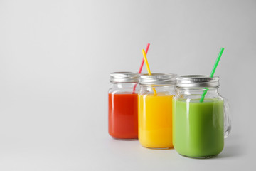 Mason jars of fresh juice on grey background