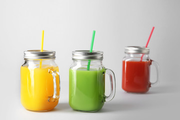 Mason jars of fresh juice on grey background