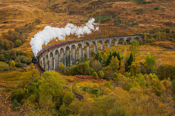 old fashioned steam train with air whistle on Glenfinnan viaduct, Scotland which is the location of many films in autumn