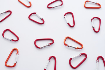 Metal constructions. Many of the red colored carabiners on lying on the white table