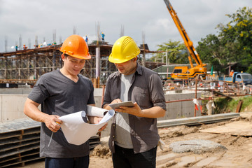 Team of construction workers discussing project details with blueprint in construction site.