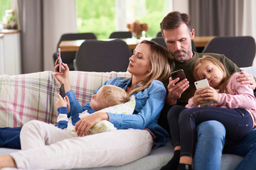 Parents and children using mobile phone in living room