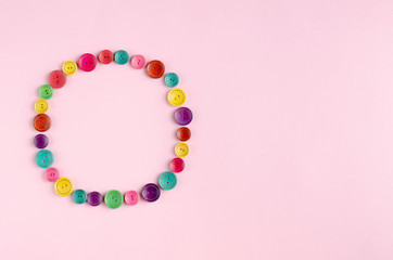 Naklejka premium Colored sewing buttons composition on pink background.