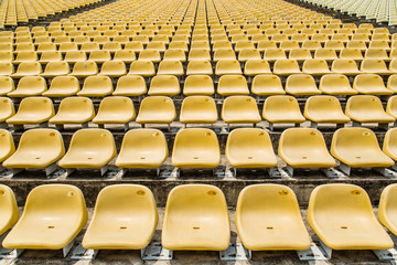 Naklejka premium yellow empty chairs on the outdoor stadium