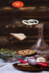 Levitation of ukrainian sandwich with lard and vegetables on the table in warm colors