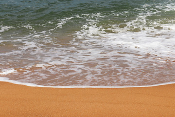 Soft ocean wave with foam on a sand. Picturesque seascape with clear water and yellow sand,...