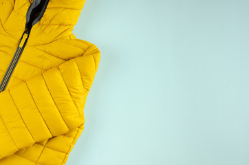 Yellow kids winter jacket composition on blue background.