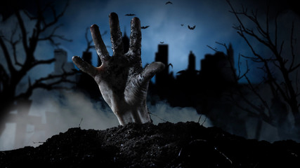 Spooky graveyard with zombie hand coming out of the ground