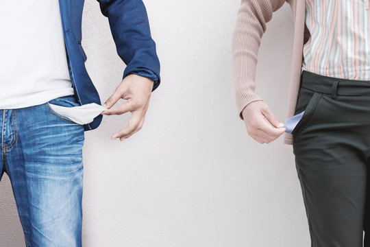 Man and woman showing empty pockets on wall background.