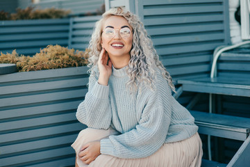 Plus size model with blond curly hair in knitted sweater outdoor