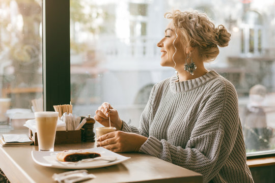 Woman Drinking Coffe By The Window In City Street Cafe