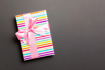 Gift box with pink bow for Christmas or New Year day on black background, top view with copy space