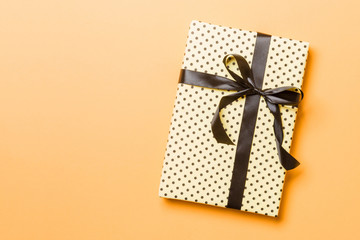 wrapped Christmas or other holiday handmade present in paper with black ribbon on orange...