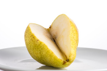 half and a quarter of a yellow pear on a white plate