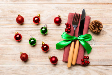 Top view of holiday set of fork and knife on wooden background. Close up of Christmas decorations and toys. New Year Eve concept