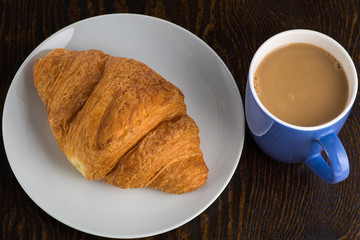 croissant on a white plate and coffee in a purple mug