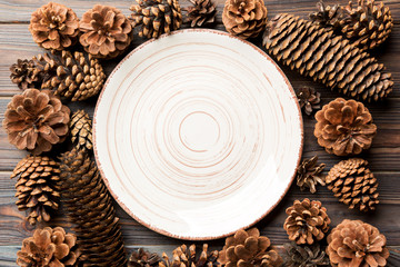 Top view of festive plate with pine cones on wooden background. New Year dinner concept