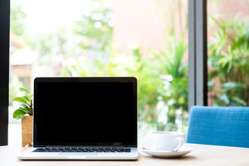 Mockup of laptop computer with empty screen with coffee cup on table of the coffee shop background