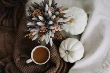 Coffee cup with flowers and pumpkins on a cozy plaid. Autumn still life. Breakfast in bed. Good morning. Stylish autumn flat lay. 